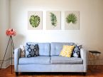 Obraz na płótnie Tropical Leaf III wiszący na białej ścianie w salonie nad niebieską kanapą