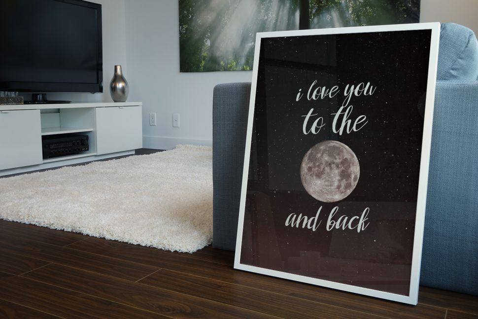 I love you to the moon and back - plakat w białej ramce drewnianej leżący w salonie na podłodze
