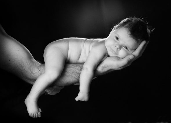 czarno-biała fototapeta przedstawiająca niemowlaka leżącego na męskiej ręce