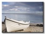canvas na ścianę przedstawiający białą łódź zacumowaną na piaszczystej plaży na tle spokojnego morza i zachmurzonego nieba