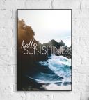 Plakat wiszący na ceglanej ścianie oprawiony w czarną ramę przedstawiający nadmorski krajobraz oraz napis ''Hello Sunshine''