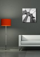 aranżacja obrazu z brooklyn bridge na szarej ścianie w pokoju nad białą sofą obok czerwonej lampy