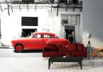 fototapeta z czerwonym samochodem przed białym budynkiem w nowoczesnym białym salonie z czarną sofą
