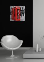 aranżacja obrazu na płótnie z czerwoną budką telefoniczną na czarnej ścianie w salonie za białym fotelem