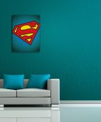 aranżacja obrazu z symbolem Supermana w pokoju z turkusową ścianą nad szarą sofą