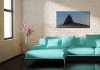Obraz na płótnie wiszący na ścianie w salonie nad turkusową kanapą przedstawia skalne wzgórze Ship Rock