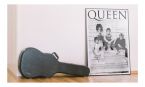 Plakat Queen oprawiony w ramkę leżącą na podłodze obok futerału na gitarę