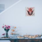 Obraz na płótnie z kolorowy symbolem Hamsa powieszony nad stołem z ciastami