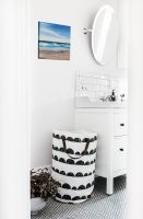 Canvas z morską scenerią wiszący w łazience na białej ścianie nad koszem na pranie