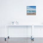 Obraz na płótnie z widokiem na morze powieszony nad białym stolikiem