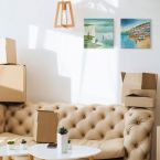 Canvasy z widokiem na klify powieszone w salonie nad beżową kanapą