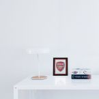 Obraz w ramie z herbem klubu piłkarskiego Arsenal postawiony na białym biurku