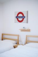Obraz przedstawiający znak metra w Londynie powieszony na białej ścianie w sypialni