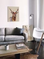 Canvas przedstawiający jelenia powieszony w stylowym salonie nad szarą kanapą