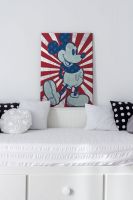 Canvas do dziecięcego pokoju z Myszką Miki na czerwono-białym pasiastym tle postawiony na białej ramie drewnianego łóżka