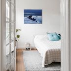 Aranżacja sypialni w której nad łóżkiem na ścianie wisi obraz przedstawiający sztorm na morzu