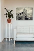 Obraz na płótnie przedstawiający Tower Bridge powieszony nad białą pikowaną kanapą w salonie