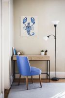 Obraz na płótnie z niebieskim skorpionem na białym tle powieszony w pokoju nad drewnianym biurkiem obok lampy