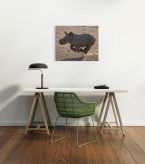 Canvas wiszący nad białym stolikiem w nowoczesnym biurze przedstawiający biegnącego małego nosorożca