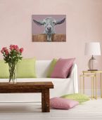 Obraz na płótnie wiszący w salonie nad kanapą z różowymi i zielonymi poduszkami przedstawiający białą kozę