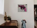 Obraz na płótnie wiszący nad zamkniętym pianinem przedstawiający różowy pistolet