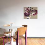Obraz z kwiatami powieszony na białej ścianie nad okrągłym stolikiem z krzesłami