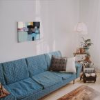 Canvas przedstawiający abstrakcję wiszący nad niebieską kanapą w pokoju