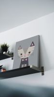 Obraz na płótnie postawiony na czarnej półce oparty o ścianę przedstawiający kotka