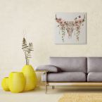 Obraz na płótnie przedstawiający kolorową czaszkę w kwiaty powieszony nad szarą kanapą w salonie