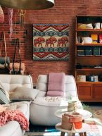 Canvas z trzema słonikami i kolorowymi wzorami powieszony na ścianie z czerwonej cegły