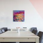 Canvas z barwnym pejzażem powieszony na białej ścianie nad drewnianym stołem