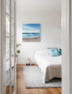 Canvas z morskim pejzażem powieszony w sypialni na białej ścianie