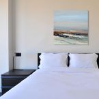 Sypialnia w której wisi obraz z morskim pejzażem