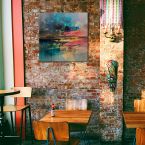 Stylowa restauracja z wiszącym na ceglanej ścianie obrazem na płótnie przedstawiającym abstrakcję