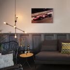 Obraz na drewnie przedstawiający Ferrari F1 powieszony nad szarą kanapą w salonie