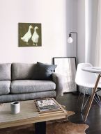 Obraz na płótnie autorstwa Julia Burns z kaczkami powieszony w salonie nad szarą kanapą