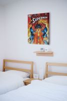 Zdjęcie pokoju hotelowego w którym powieszony jest obraz na płótnie z Supermanem