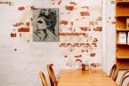 Aranżacja stylowej restauracji w której powieszono obraz Loui Jovera na ceglanej ścianie