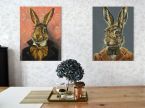 Obraz na płótnie z królikiem w ubraniu zawieszony na kwiecistej ścianie nad drewnianym stołem obok obrazu z drugim królikiem