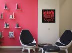 Obraz z czerwonym logiem serialu Stranger Things powieszony w pokoju nad czarnym stolikiem i biało-czarnymi okrągłymi krzesłami