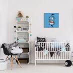 Niebieski obraz z dżinem z bajki Aladyn powieszony w pokoju dziecka nad łóżeczkiem obok regału z zabawkami