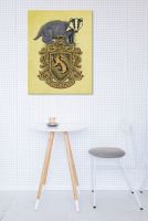 Obraz na płótnie z herbem Hufflepuffu powieszony na białej ścianie nad stolikiem