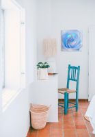 Obraz z błękitną różą wiszący na ścianie w jasnym pomieszczeniu z turkusowym krzesłem