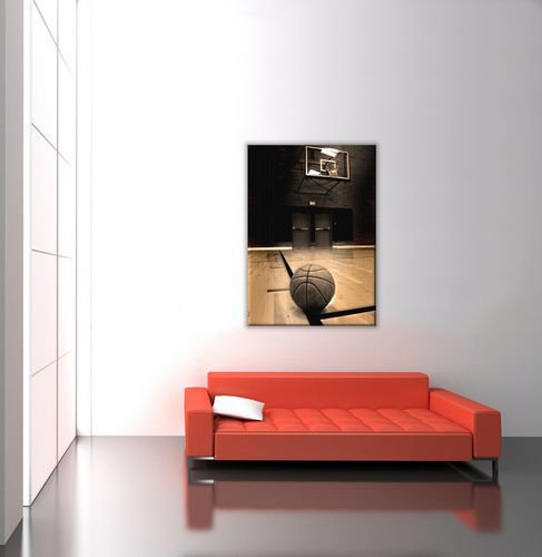 aranżacja obrazu na płótnie przedstawiającego piłkę do koszykówki na tle hali sportowej i kosza na białej ścianie w salonie nad dużą pomarańczową sofą