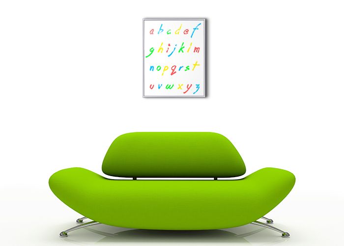 aranżacja małego plakatu z alfabetem w srebrnej ramie zawieszonego nad zieloną sofą