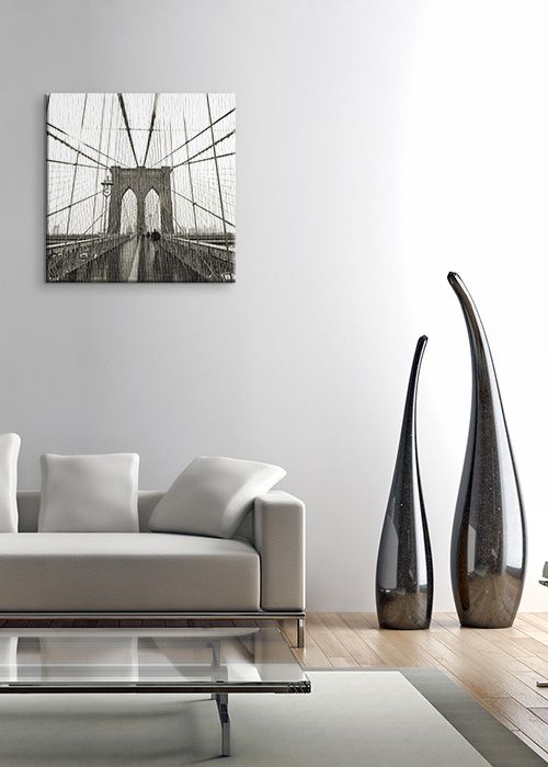 aranżacja obrazu z Brooklyn Bridge w salonie z białymi ścianami nad wygodną sofą