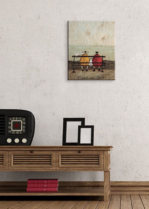 aranżacja obrazu z parą wpatrującą się w morze w pokoju z białymi ścianami nad drewnianym biurkiem