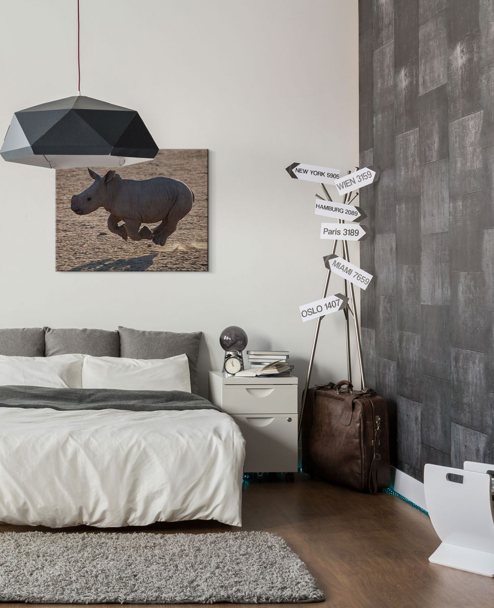 Obraz wiszący na ścianie w sypialni nad łóżkiem przedstawiający nosorożca w biegu