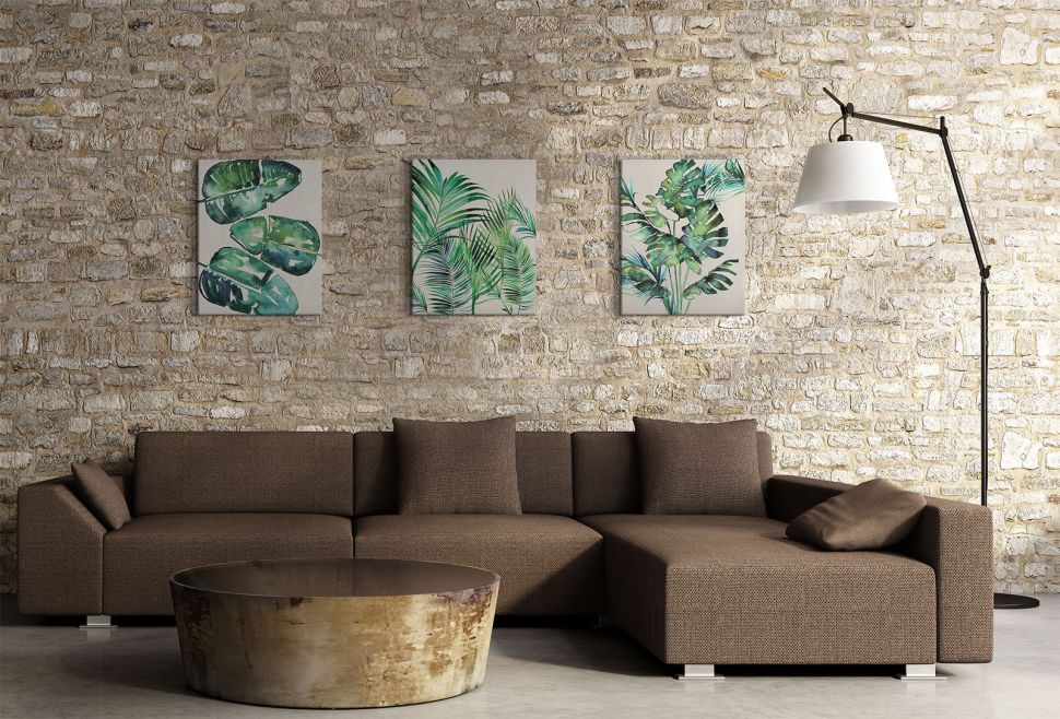 Obrazy naścienne wiszące nad kanapą w salonie przedstawiające zielone liście