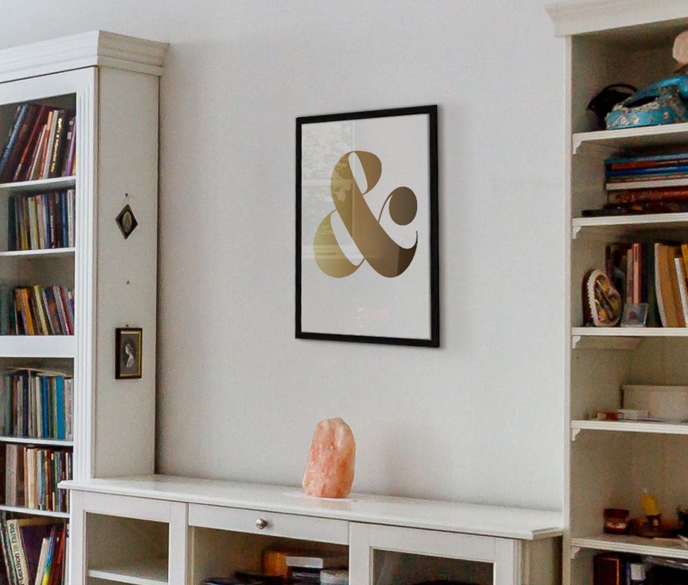 Plakat wiszący w salonie nad szafką z książkami oprawiony w czarną ramę przedstawiający znak ''&''